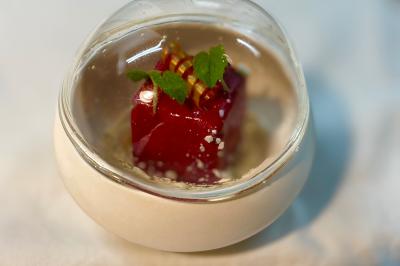 Coucher de soleil rougeoyant derrière une rangée d'arbres, vu depuis une terrasse avec mobilier et voitures garées.