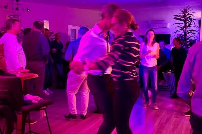 Coucher de soleil rougeoyant derrière une rangée d'arbres, vu depuis une terrasse avec mobilier et voitures garées.