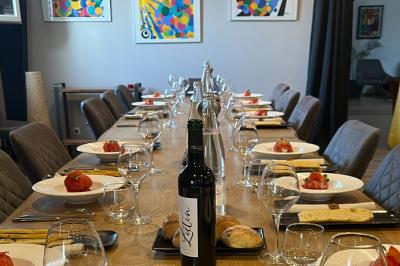 Coucher de soleil rougeoyant derrière une rangée d'arbres, vu depuis une terrasse avec mobilier et voitures garées.