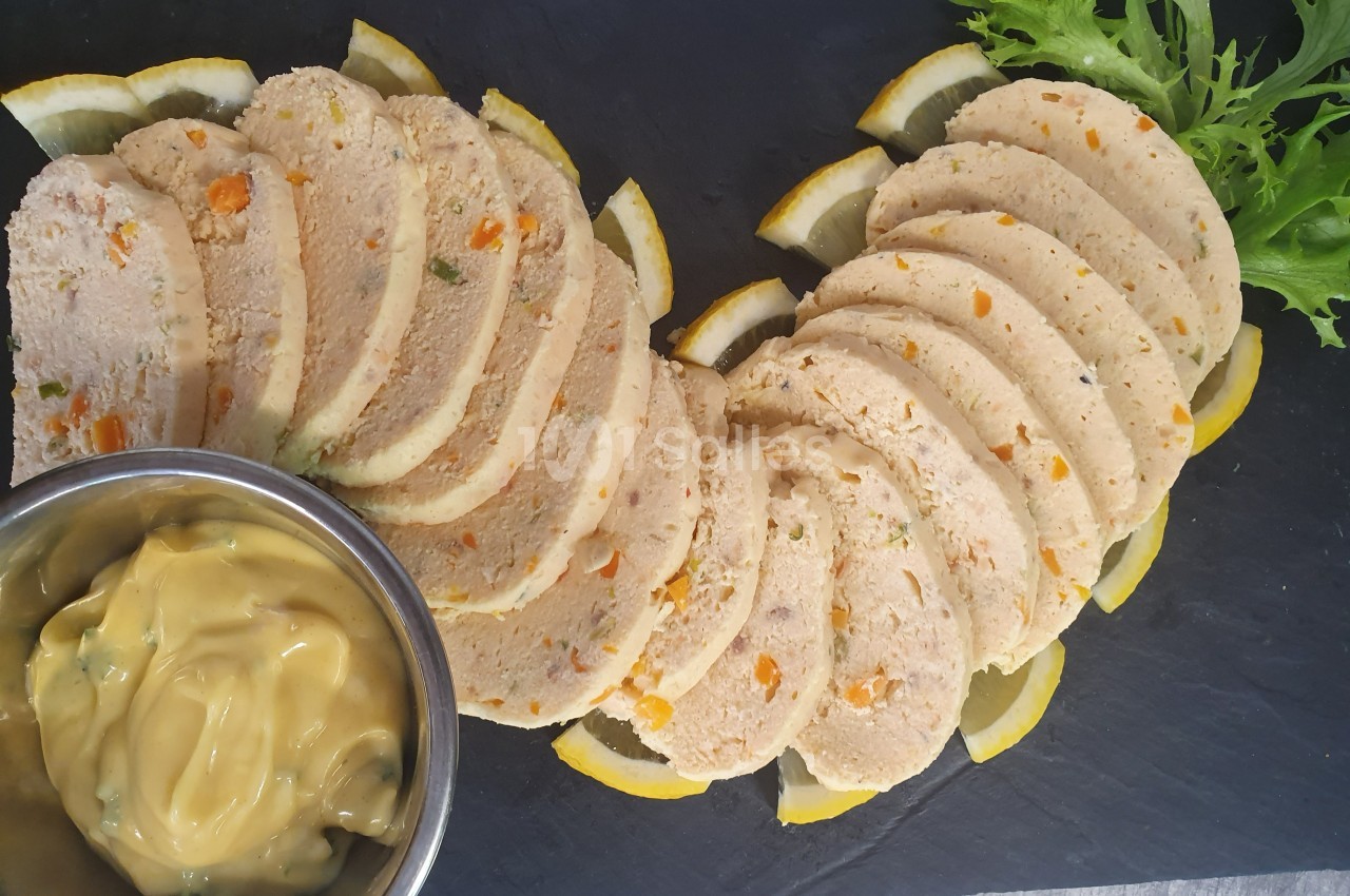 Tranches de terrine de volaille aux légumes disposées en éventail sur un plateau, accompagnées de sauce et de salade verte.
