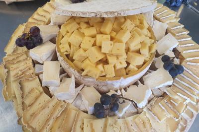 Plateau de légumes croquants, dips et charcuterie disposés sur une table en extérieur, avec des décorations végétales.