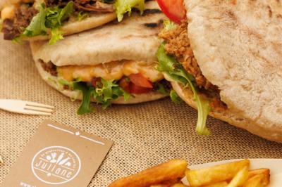 Plateau de légumes croquants, dips et charcuterie disposés sur une table en extérieur, avec des décorations végétales.