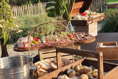 Plateau de légumes croquants, dips et charcuterie disposés sur une table en extérieur, avec des décorations végétales.