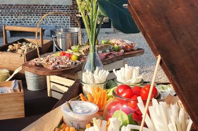 Plateau de légumes croquants, dips et charcuterie disposés sur une table en extérieur, avec des décorations végétales.