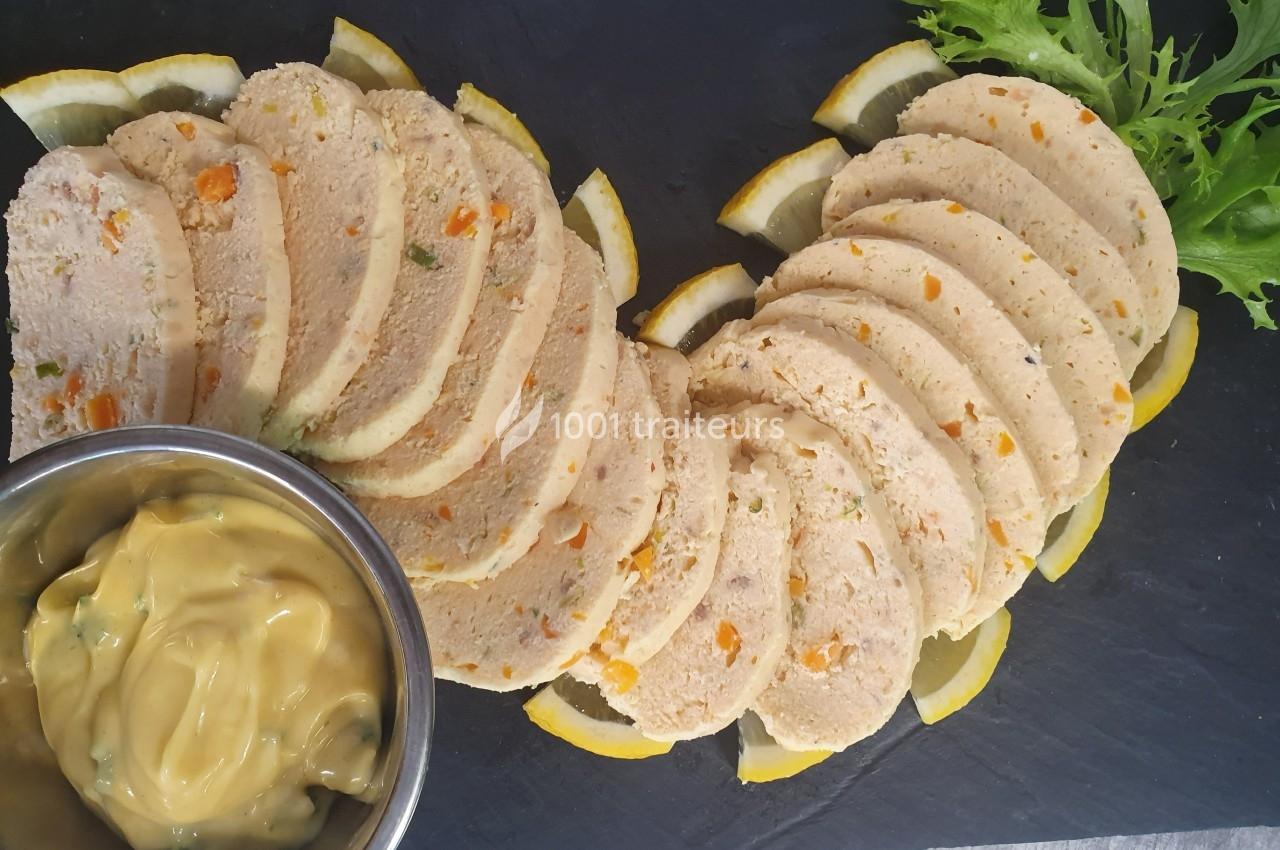 Tranches de terrine de volaille aux légumes disposées en éventail sur un plateau, accompagnées de sauce et de salade verte.