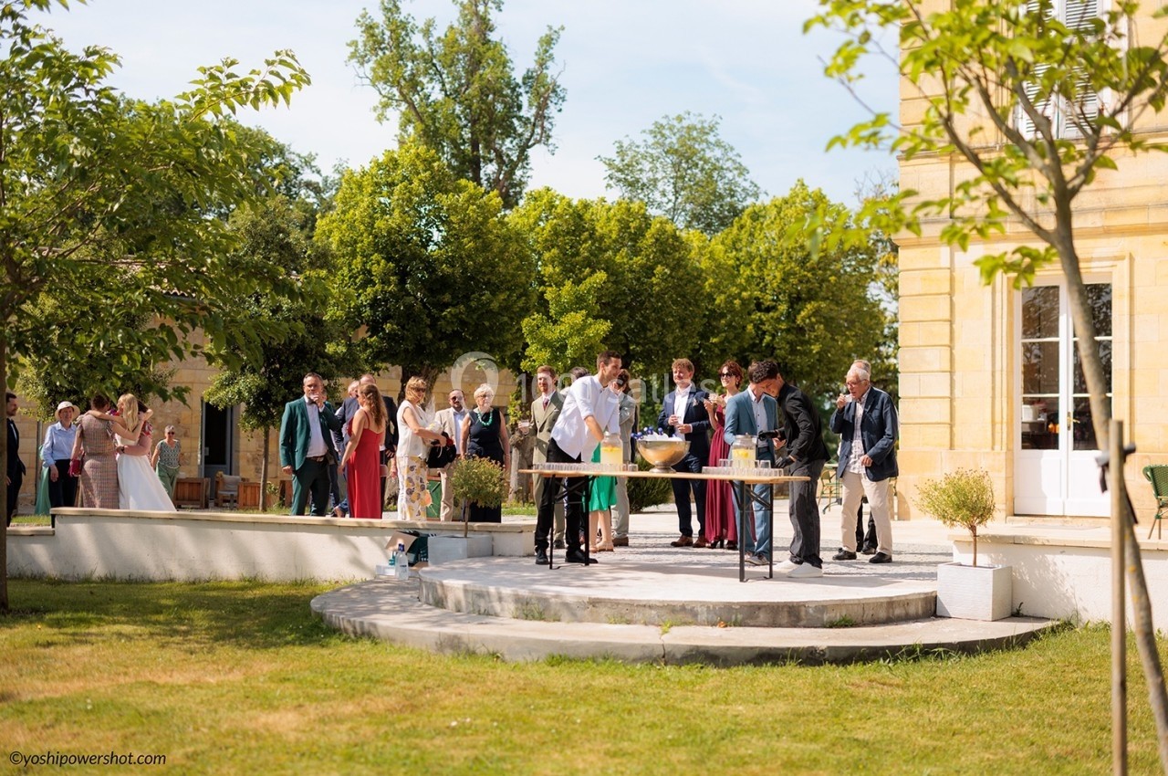 Groupe de personnes rassemblées en extérieur près d'une table de buffet, dans un jardin par une journée ensoleillée.