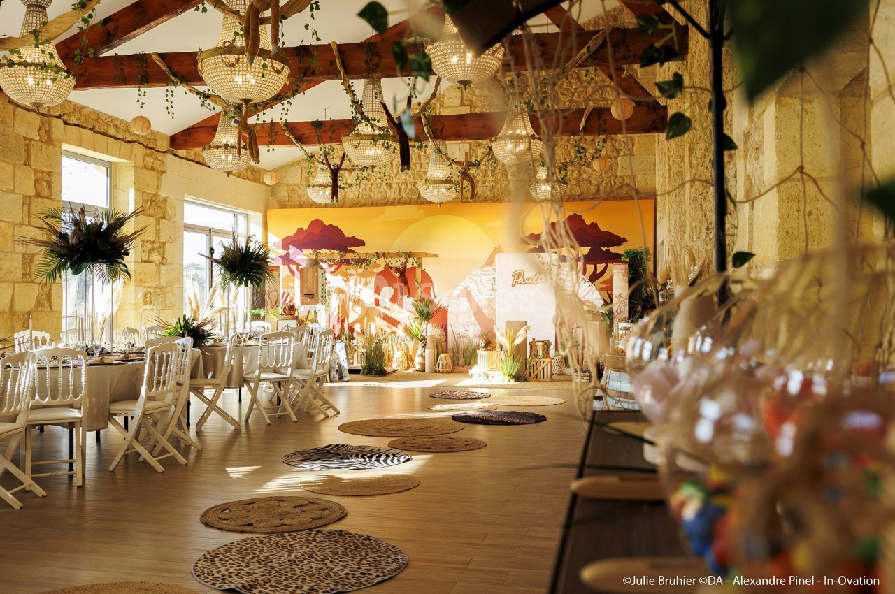 Salle de réception décorée sur le thème safari, avec tables dressées, fresques murales et luminaires suspendus.