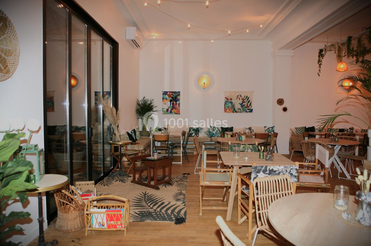 Salle lumineuse avec décoration végétale, mobilier en bois et éclairage chaleureux, ambiance conviviale.
