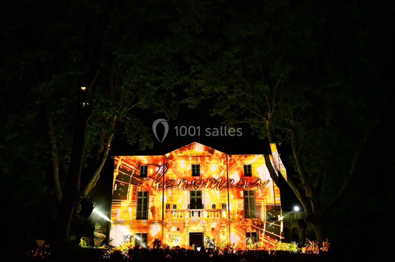 Façade d'un bâtiment illuminée par des projections lumineuses colorées dans un environnement nocturne.