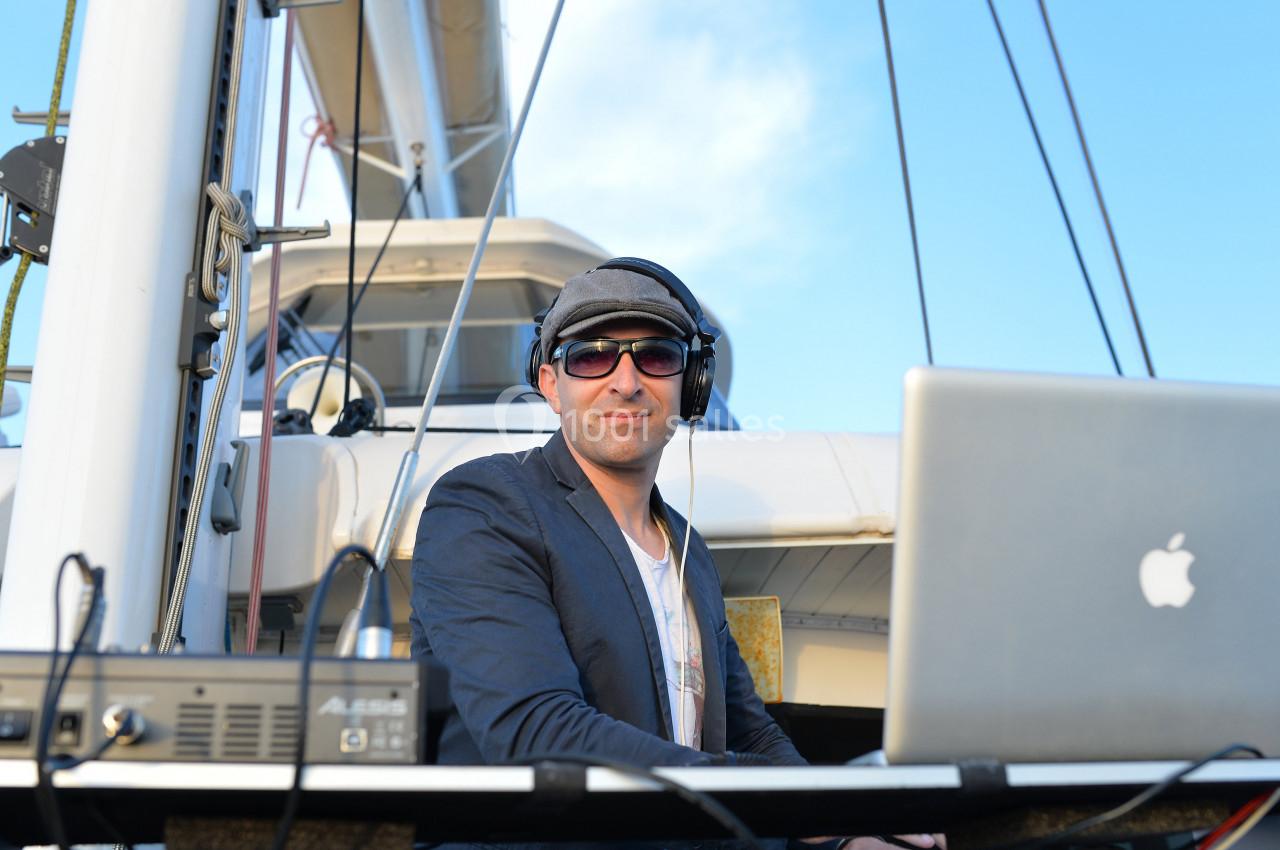 Un homme portant un casque audio travaille sur un ordinateur portable à bord d'un bateau sous un ciel dégagé.