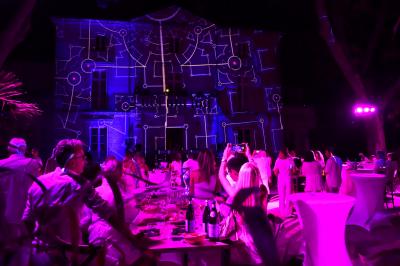 Façade d'un bâtiment illuminée par des projections lumineuses colorées dans un environnement nocturne.