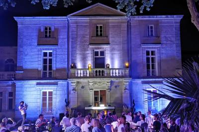 Façade d'un bâtiment illuminée par des projections lumineuses colorées dans un environnement nocturne.