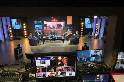 Cinq personnes discutent sur un plateau télévisé, avec un écran diffusant une intervention en visioconférence.