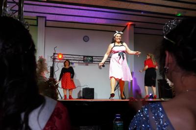 Bouteille en verre remplie de liquide brun, fermée par un bouchon blanc, sur un fond sombre.