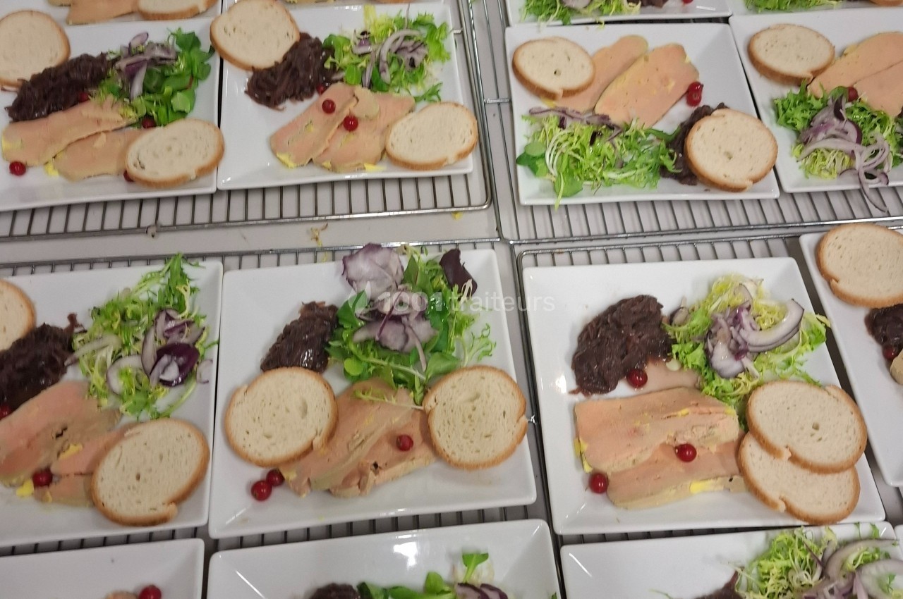 Assiettes dressées avec foie gras, pain, salade verte, oignons rouges, confit d'oignons et airelles rouges.