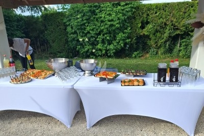 Salle décorée avec rideaux bleus, guirlandes lumineuses, vases avec fleurs et table recouverte d'une nappe blanche.