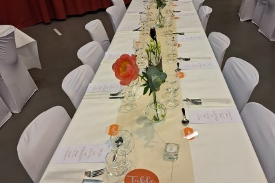 Salle décorée avec rideaux bleus, guirlandes lumineuses, vases avec fleurs et table recouverte d'une nappe blanche.