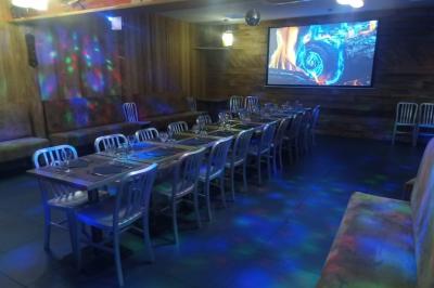 Salle de restaurant avec longues tables dressées, éclairage tamisé et effets lumineux colorés sur le sol.