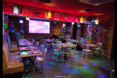 Salle de restaurant avec longues tables dressées, éclairage tamisé et effets lumineux colorés sur le sol.