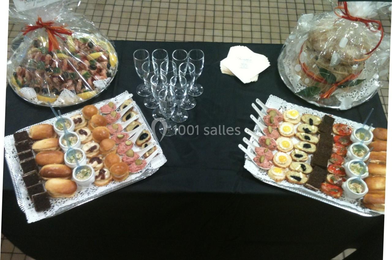 Plateau de buffet avec verrines, amuse-bouches variés et desserts, entouré de paniers garnis et flûtes à champagne.