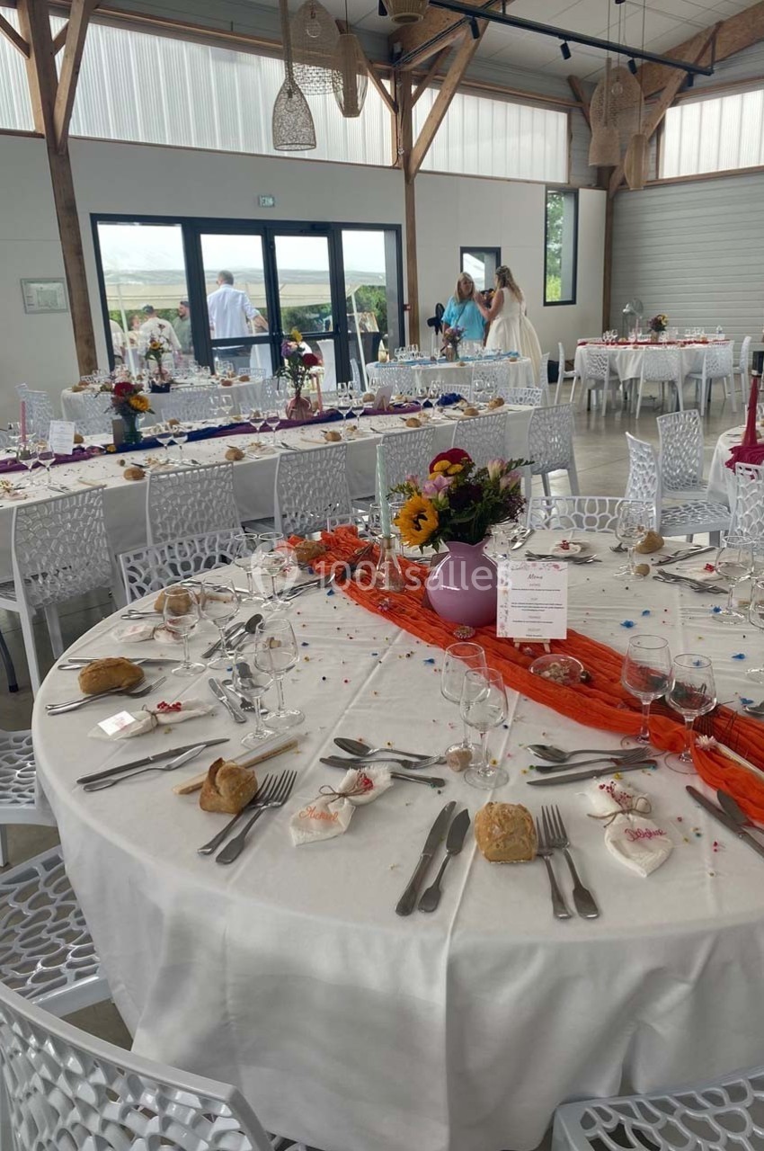 Tables décorées pour un événement avec nappes blanches, chemins de table colorés, vaisselle et compositions florales.