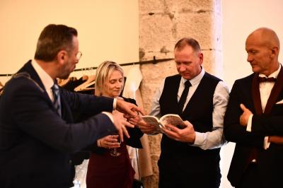 Miniature Ludovic Magicien #2 Un homme en costume effectue un tour de magie avec des cartes devant un petit groupe de personnes souriantes.