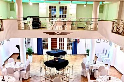 Miniature Location salle Bruxelles (Bruxelles-Capitale) - La Salle Montoyer Bruxelles #4 Salle de réception lumineuse avec tables rondes dressées, chaises blanches et éclairage violet au plafond.