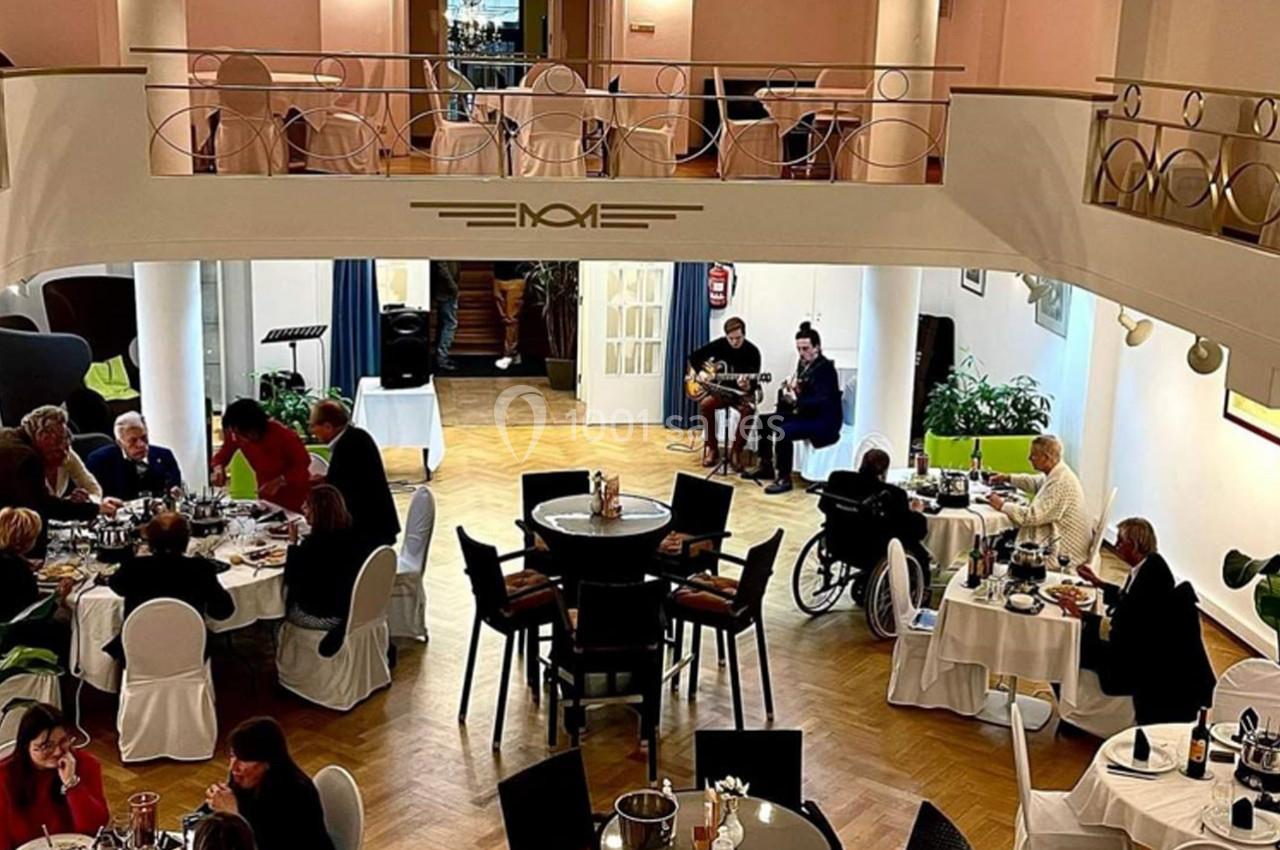 Salle de restaurant élégante avec des convives attablés, un musicien et une chanteuse se produisant en arrière-plan.