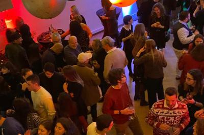 Intérieur d'un café lumineux avec canapés colorés, grandes fenêtres donnant sur une rue et un bar en arrière-plan.
