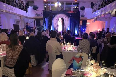 Intérieur d'un café lumineux avec canapés colorés, grandes fenêtres donnant sur une rue et un bar en arrière-plan.