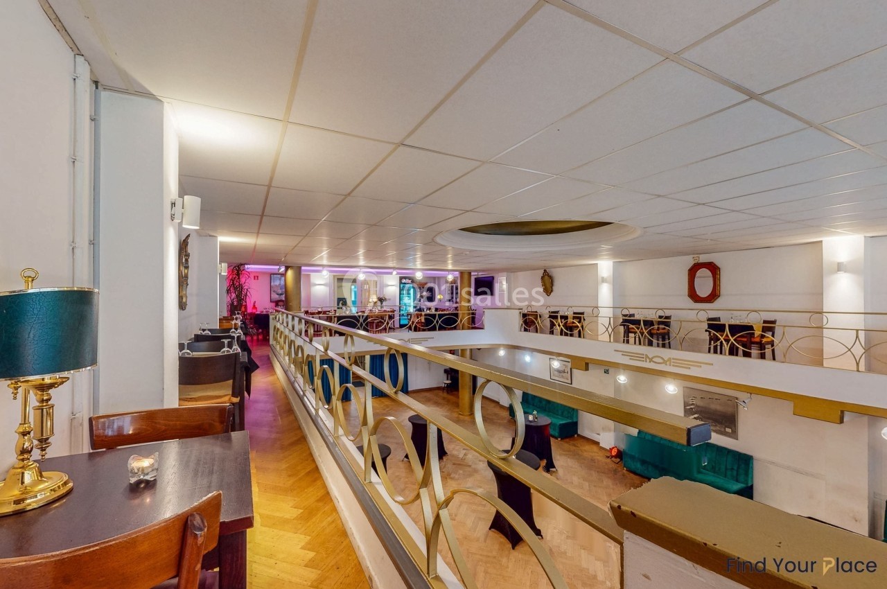 Vue intérieure d'un espace avec mezzanine, mobilier en bois, éclairage tamisé et décoration moderne.