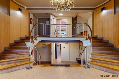 Intérieur d'un café lumineux avec canapés colorés, grandes fenêtres donnant sur une rue et un bar en arrière-plan.
