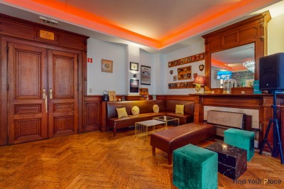 Intérieur d'un café lumineux avec canapés colorés, grandes fenêtres donnant sur une rue et un bar en arrière-plan.