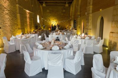 Salle de réception décorée avec des tables rondes, nappes blanches, éclairage rouge et arrangements floraux suspendus.