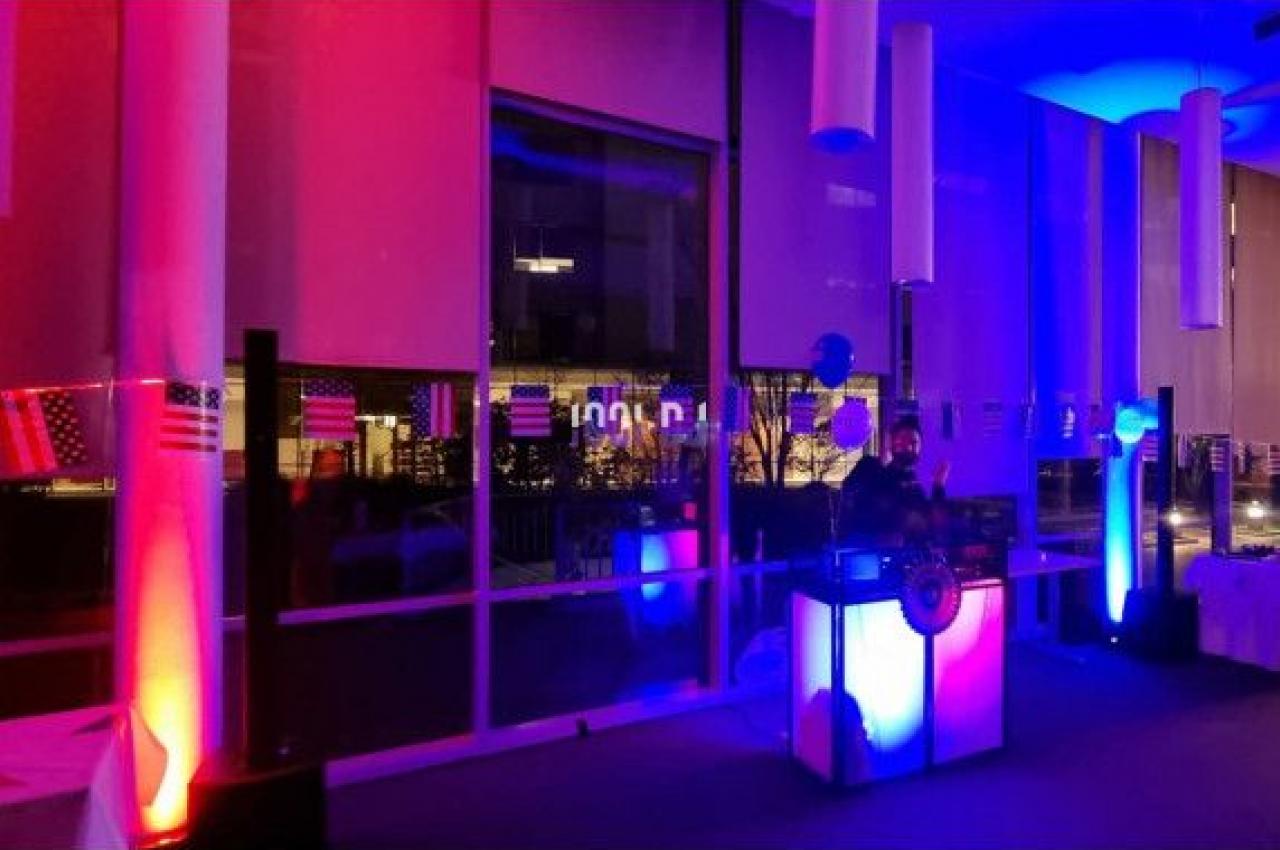 Installation lumineuse avec des éclairages rouges et bleus dans une salle avec de grandes baies vitrées en arrière-plan.