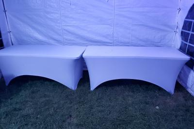 Grande tente blanche avec fenêtres en arc, installée sur un parking entouré de végétation.