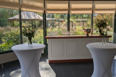 Tente éclairée par des guirlandes lumineuses dans un jardin verdoyant au crépuscule.