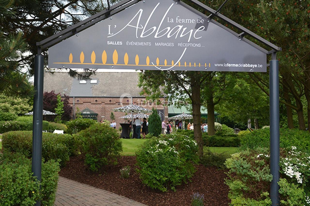 Entrée d'un domaine avec un panneau indiquant ’La ferme de l'Abbaye’, entouré de verdure et d'arbres.