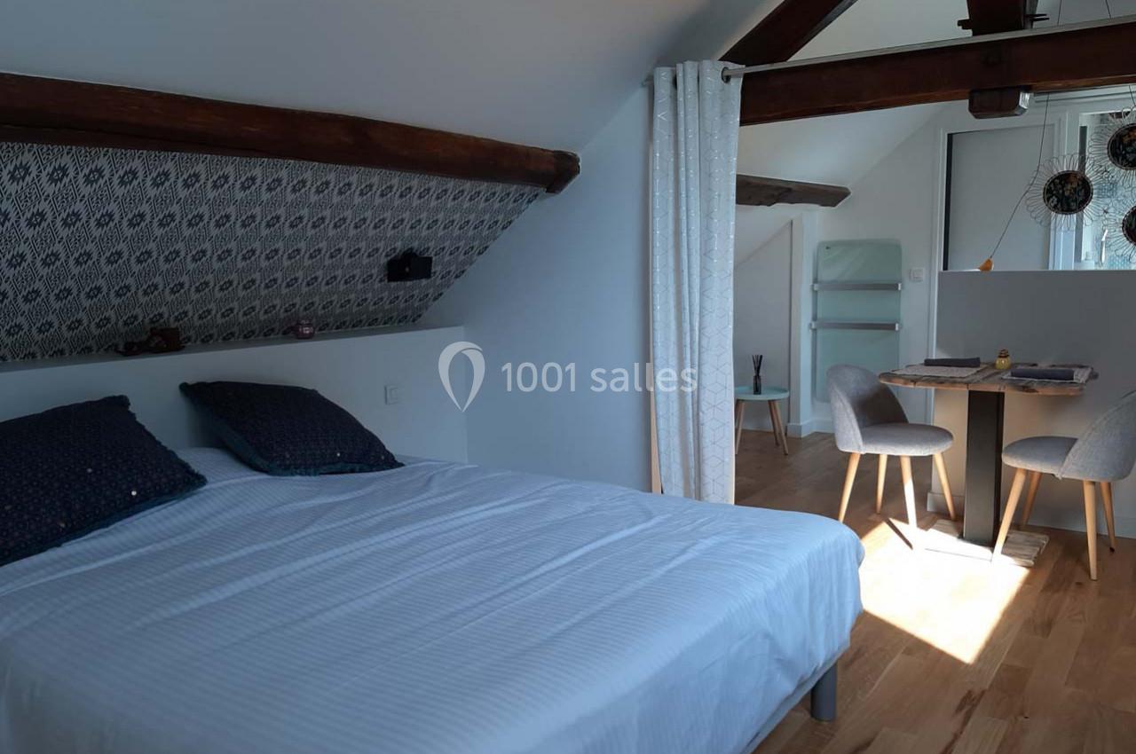 Location salle Bailleau-l'Évêque (Eure-et-Loir) - Le Domaine du Moulin 28 & SPA #30 Chambre mansardée avec lit double, table à manger, chaises et poutres apparentes, éclairée par une fenêtre.