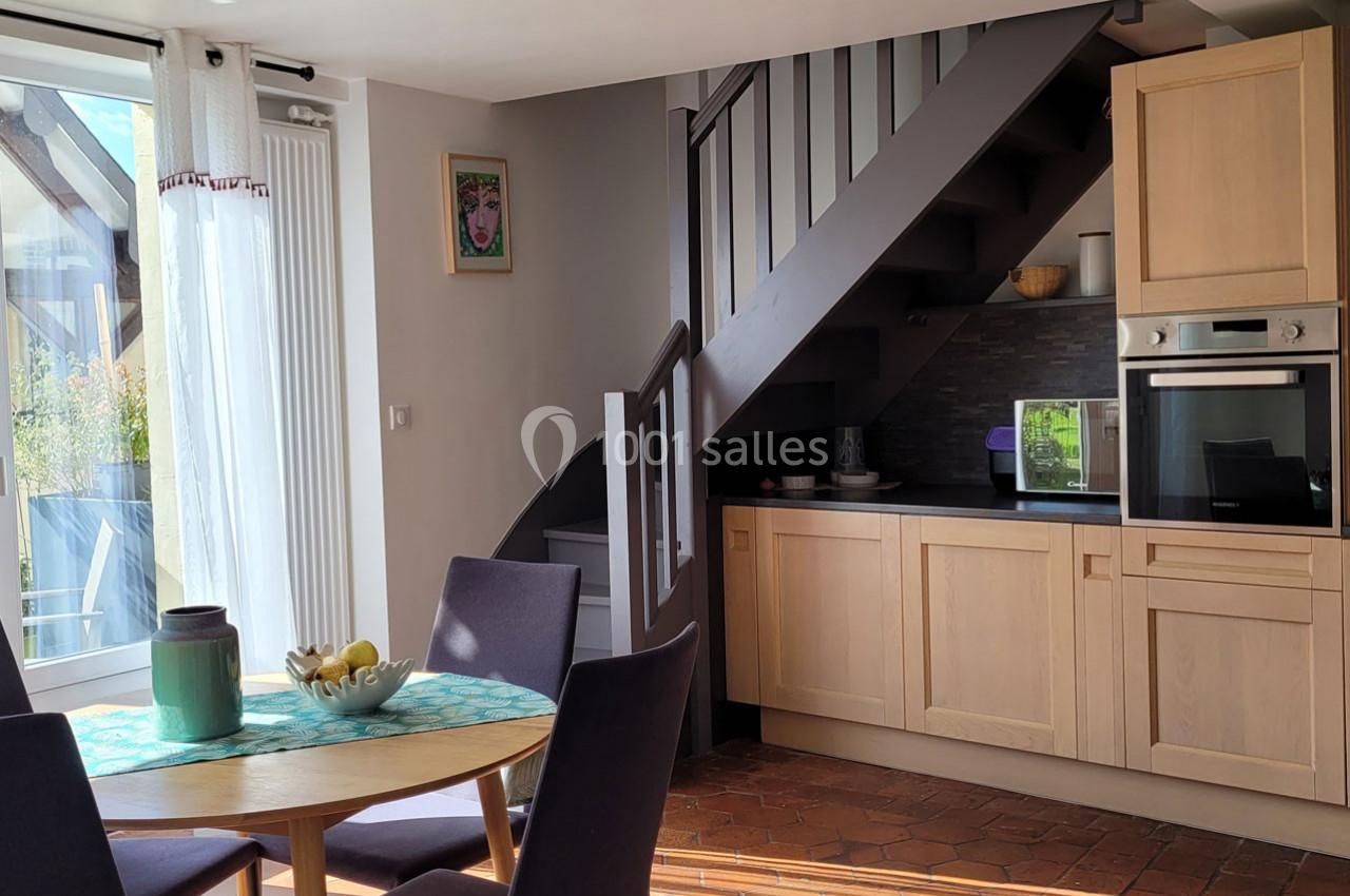 Location salle Bailleau-l'Évêque (Eure-et-Loir) - Le Domaine du Moulin 28 & SPA #27 Cuisine ouverte avec escalier en bois, table ronde dressée et lumière naturelle entrant par une baie vitrée.