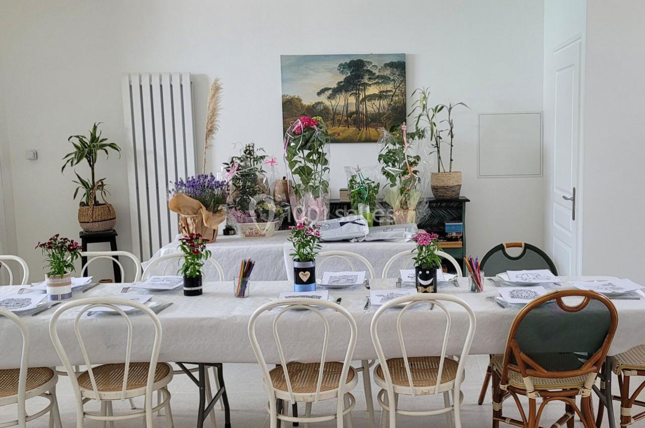 Location salle Bailleau-l'Évêque (Eure-et-Loir) - Le Domaine du Moulin 28 & SPA #18 Salle lumineuse avec deux tables décorées de plantes, fleurs et fournitures de dessin, entourées de chaises variées.