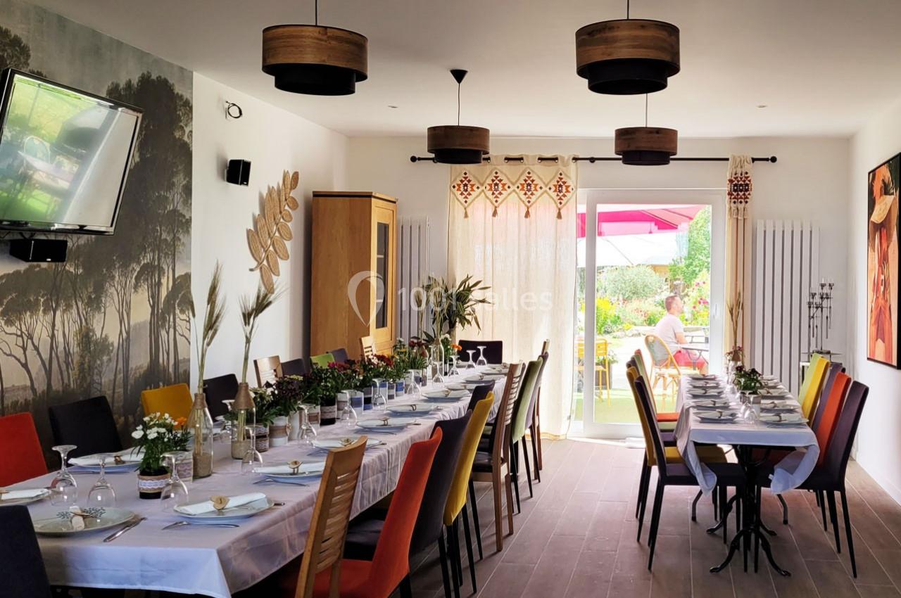 Location salle Bailleau-l'Évêque (Eure-et-Loir) - Le Domaine du Moulin 28 & SPA #12 Salle à manger lumineuse avec une grande table dressée, chaises colorées et vue sur un jardin ensoleillé.