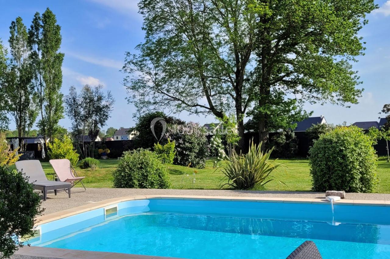 Location salle Bailleau-l'Évêque (Eure-et-Loir) - Le Domaine du Moulin 28 & SPA #9 Piscine extérieure entourée de verdure avec des chaises longues, un jardin arboré et un ciel dégagé en arrière-plan.