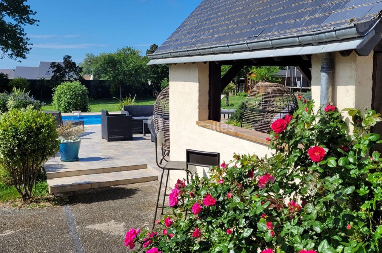 Location salle Bailleau-l'Évêque (Eure-et-Loir) - Le Domaine du Moulin 28 & SPA #7 Jardin avec terrasse, piscine, rosiers en fleurs et mobilier d'extérieur sous un ciel dégagé.