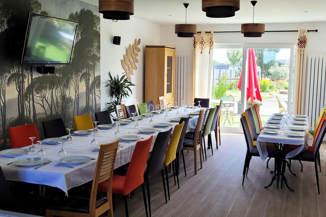 Location salle Bailleau-l'Évêque (Eure-et-Loir) - Le Domaine du Moulin 28 & SPA #13 Salle à manger lumineuse avec de longues tables dressées, des chaises colorées et une vue sur un jardin extérieur.