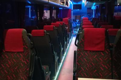 Miniature CVF Transport #6 Intérieur d'un autocar avec sièges rouges, éclairage tamisé et allée centrale recouverte d'un tapis rouge.