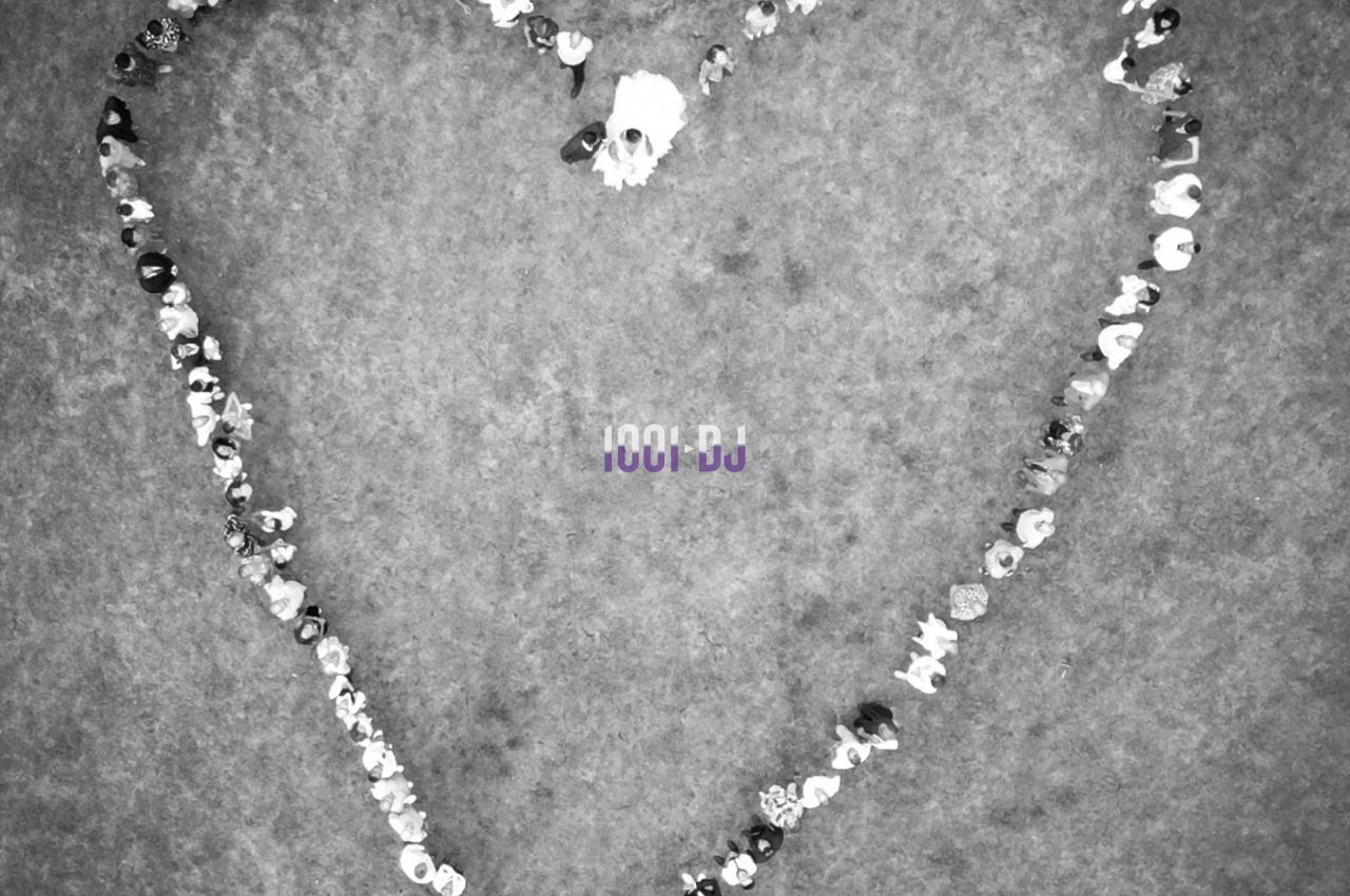 Des personnes forment un grand cœur en se tenant debout sur une pelouse vue d'en haut.