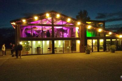 Vieille tour en briques rouges avec des fenêtres, entourée de végétation et d'un ciel bleu clair.