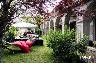 Vieille tour en briques rouges avec des fenêtres, entourée de végétation et d'un ciel bleu clair.