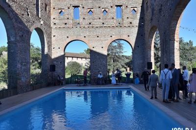 Vieille tour en briques rouges avec des fenêtres, entourée de végétation et d'un ciel bleu clair.